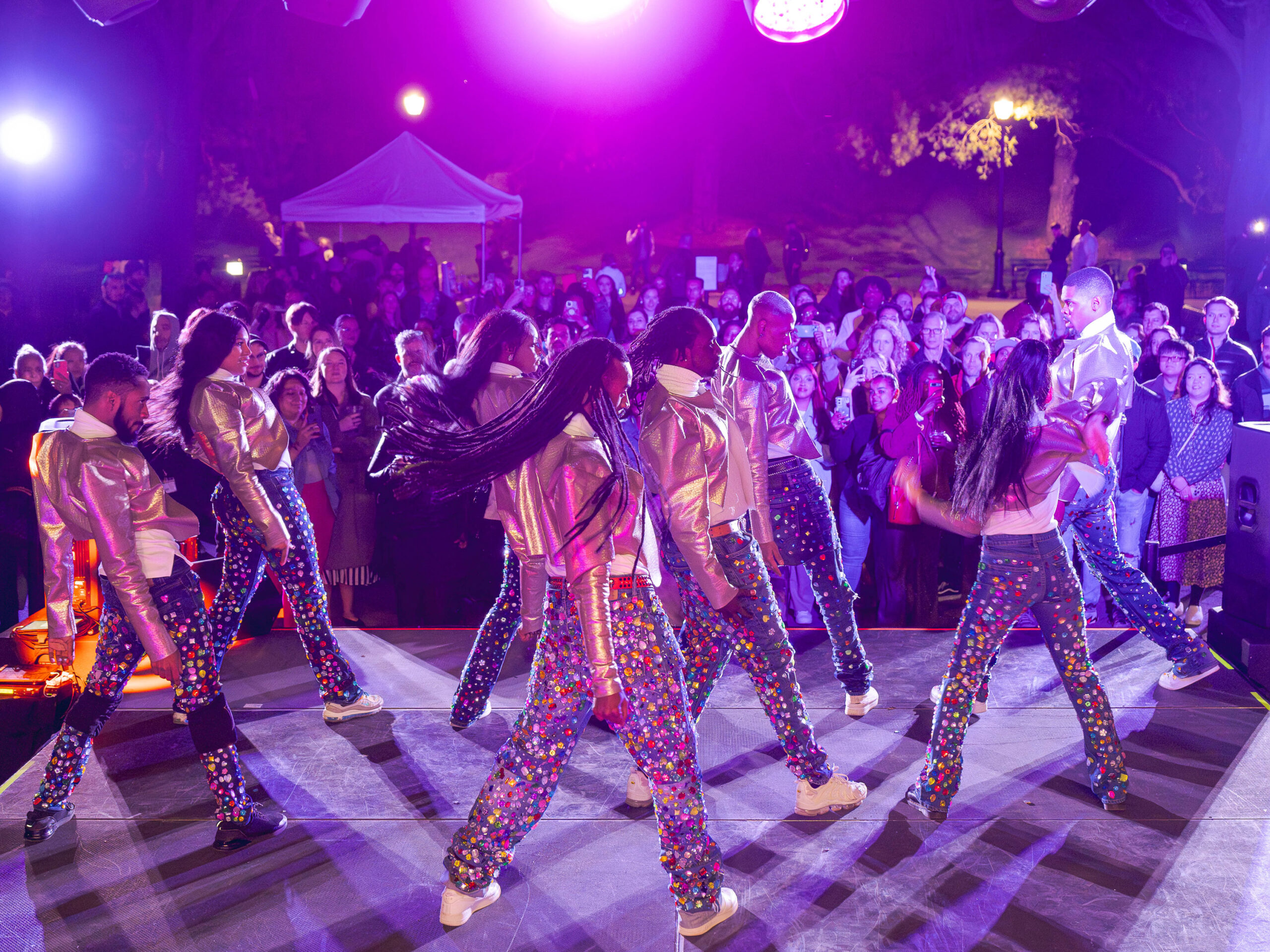A group of dancers in colorful outfits strikes a pose on stage