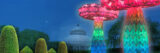 Large, rainbow-colored, illuminated mushrooms light up the night outdoors