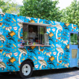 a blue food truck that is designed with images of mushrooms, hats, and teacups