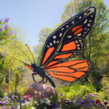 A black and orange butterfly sculpture in a sunny garden setting