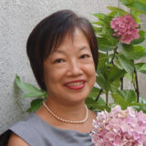 A person poses for a photo with a bouquet of pink flowers