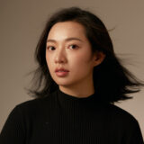 A person in a black sweater poses for a photo