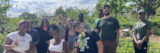 A group of gardeners pose for a photo in a garden on a sunny day