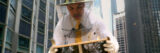 A person in a beekeeping outfit works with a hive