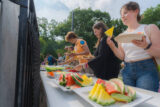 People take slices of watermelon at a barbecue.