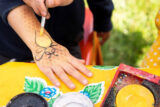 A child gets their hand painted with a festive yellow bumble bee