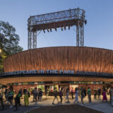 An outdoor theater lit up after dark, with people walking nearby