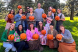 a group of people pose with carved jack-o-lanterns