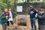 People pose for a photo while gathered around a compost bin system