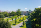 Paths lined with trees lead up to a large, classically designed building with a dome on top