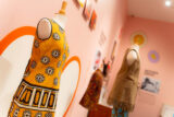 Dress forms show off vintage yellow and brown garments in a pink room