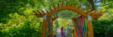 A parent and child walk through a decorative gate labeled "Everett Children's Adventure Garden" and surrounded by green foliage