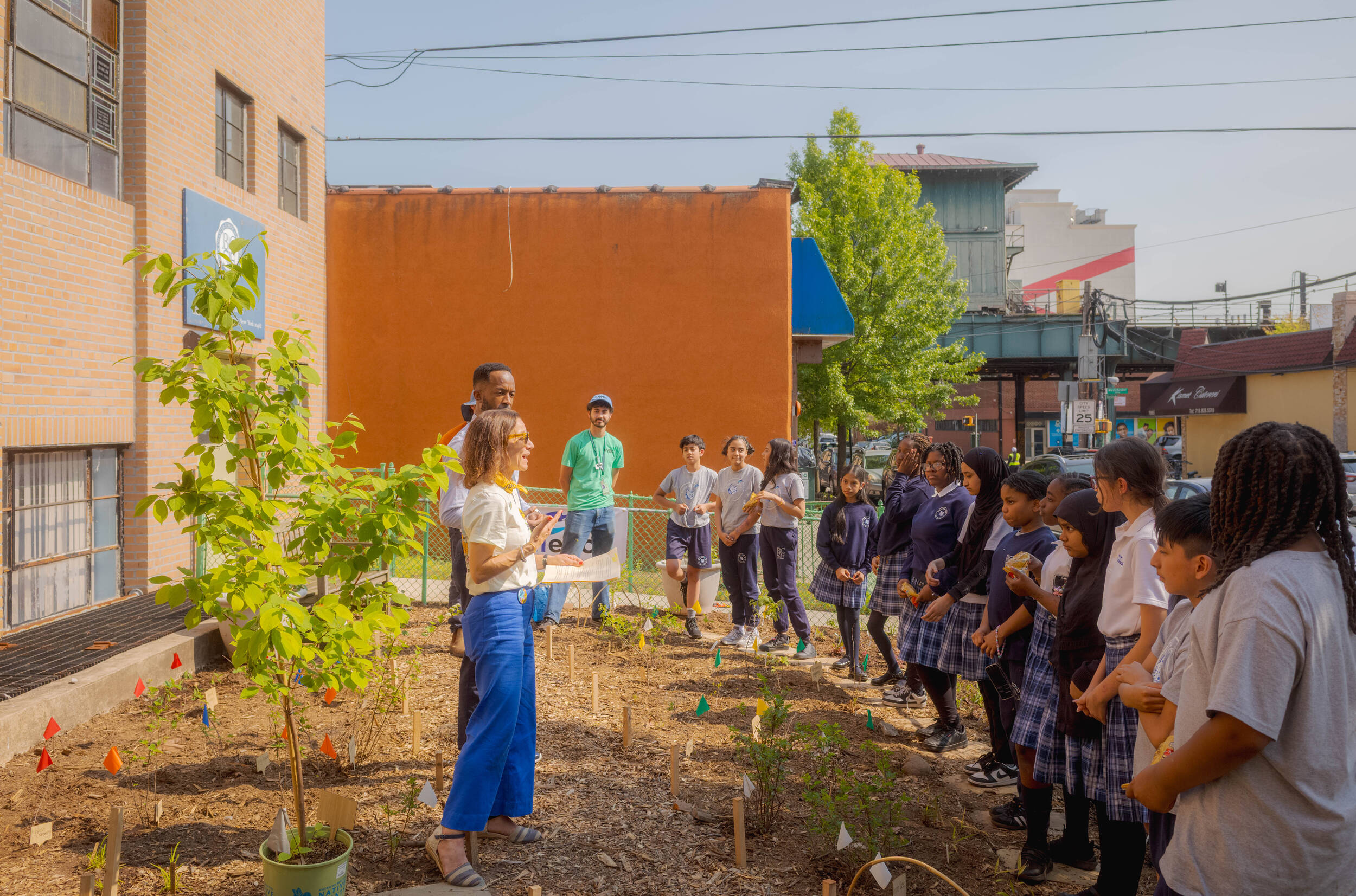 An instructor addresses a group of students in an outdoor garden