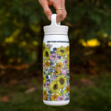 A person holds up a white water bottle with a floral pattern