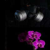 A person in a black gas mask accompanied by vivid purple flowers