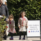 A parent and two children pose for a photo on a sunny day