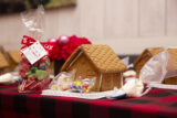 A brown gingerbread house surrounded by candy and red tablecloth