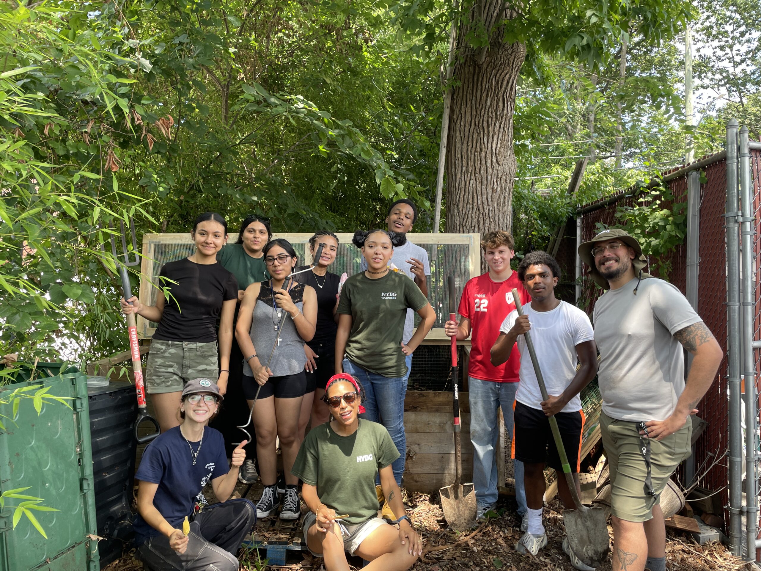 A group of people stand around a compost bin.
