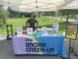 A person standing behind a table with information on Bronx Green-Up.