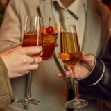 Three people toast each other with drinks in champagne flutes