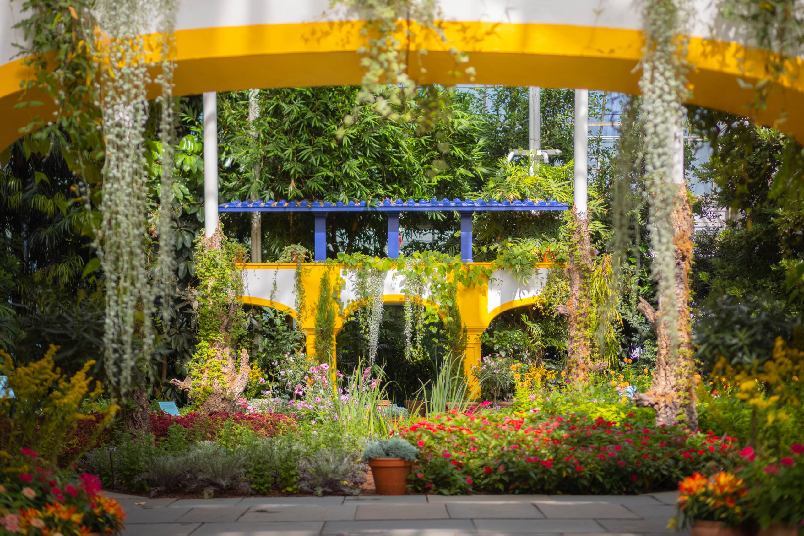 A colorful flower exhibition among yellow and blue architecture in a conservatory