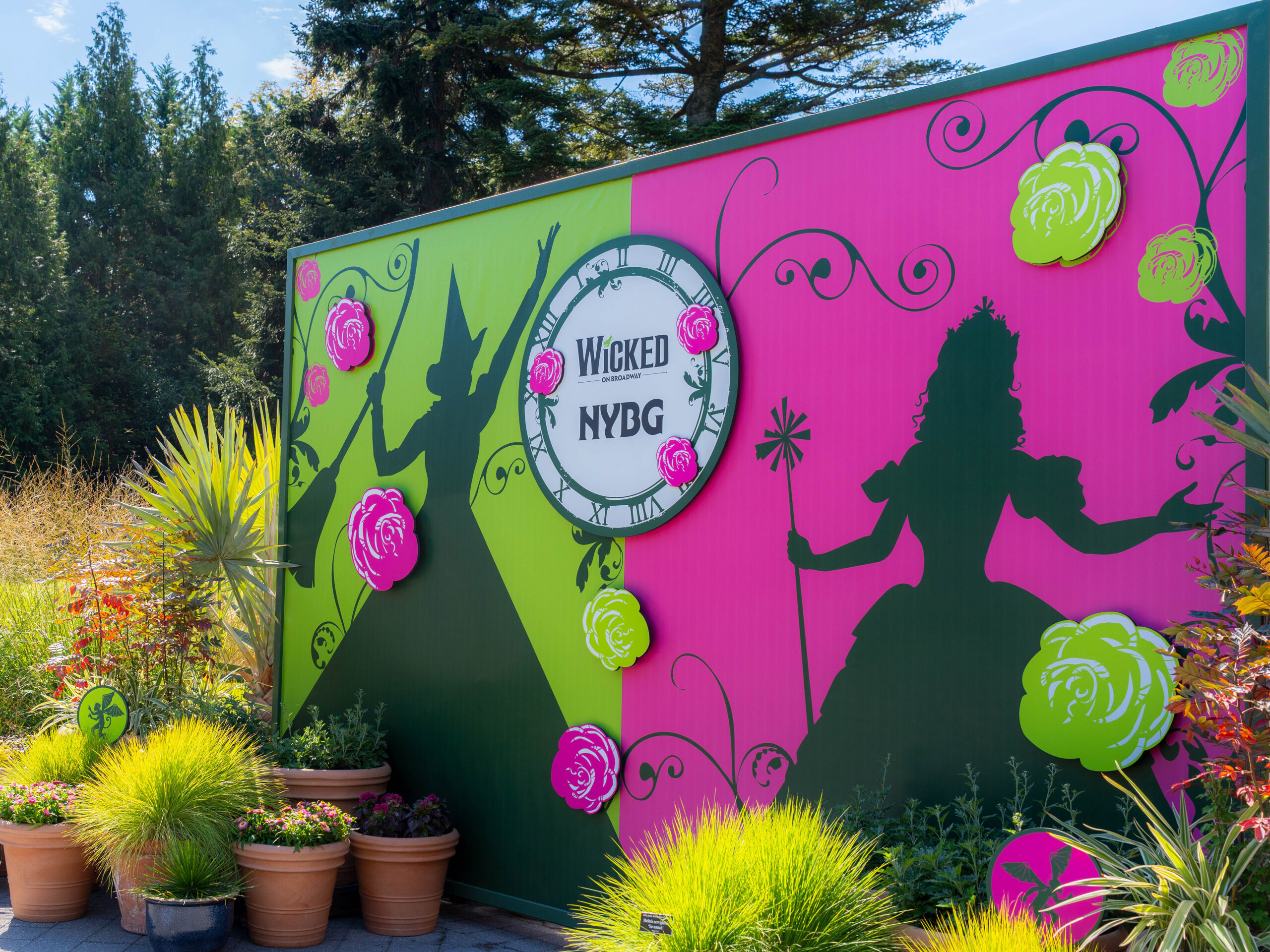 A pink and green sign depicting witches and the words "WICKED NYBG"
