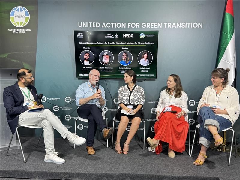 Five people sit in a circle under a sign that says "United Action for Green Transition."