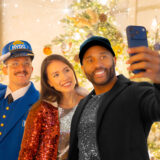 People pose for a photo with a train conductor, each wearing sparkling outfits