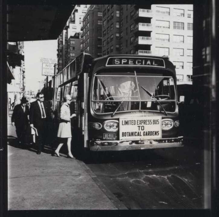A black and white photo of people boarding a bus in a city setting