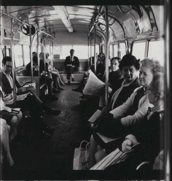 A black and white photo of people riding a bus