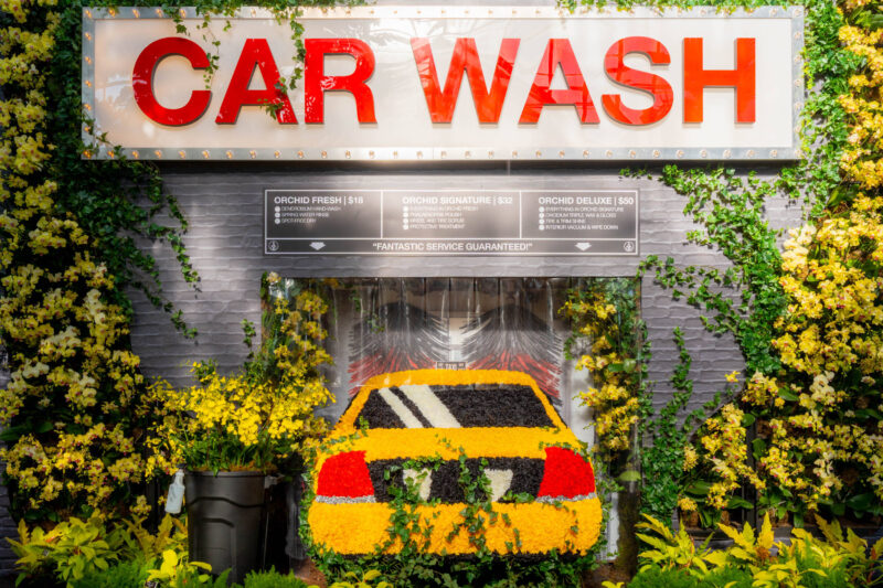 A yellow taxi cab in a car wash, rendered in colorful flowers