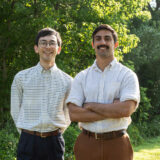 Two people in button-up shirts pose for a photo on a sunny day outdoors