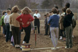 A person in a white shirt and black slacks teaches teenagers about gardening in this antique photo