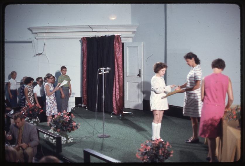 Students receive diplomas on a stage in this antique photo