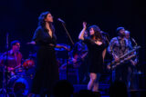 A band plays on a dimly lit stage under purple light
