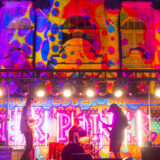 A band performs on a colorfully lit stage