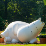 A statue of a sleeping white creature in a sunny setting