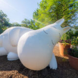 A large white creature statue adopts a sleeping pose in the sunshine