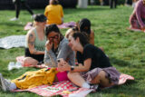 A group of runners sit on a picnic blanket and laugh together