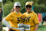 Two people in hats and yellow shirts pose for a photo
