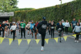 An instructor guides a group of runners in stretching before an event