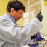 A person in a lab coat performs experiments in a lab