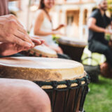 A group of people play hand drums outdoors