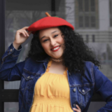A person in a red beret and yellow dress poses for a photo