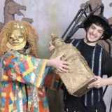 Two people in colorful costumes pose for a photo