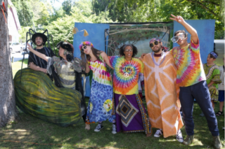 A group of people in tie-dye outfits pose outdoors