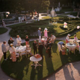 A group of people in cocktail attire enjoy a garden party at sunset