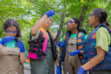 Four teenagers wearing protective glasses and life vests perform experiments with pipettes