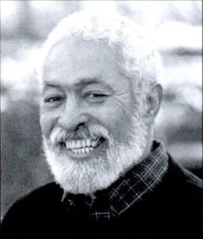 A black and white photo of a person with short white hair and a beard, posing for a photo