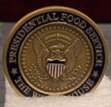 A photo of a presidential coin for the Presidential Food Service with an eagle in the center.